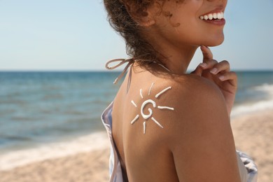 Photo of African American woman with sun protection cream on shoulder at beach, closeup