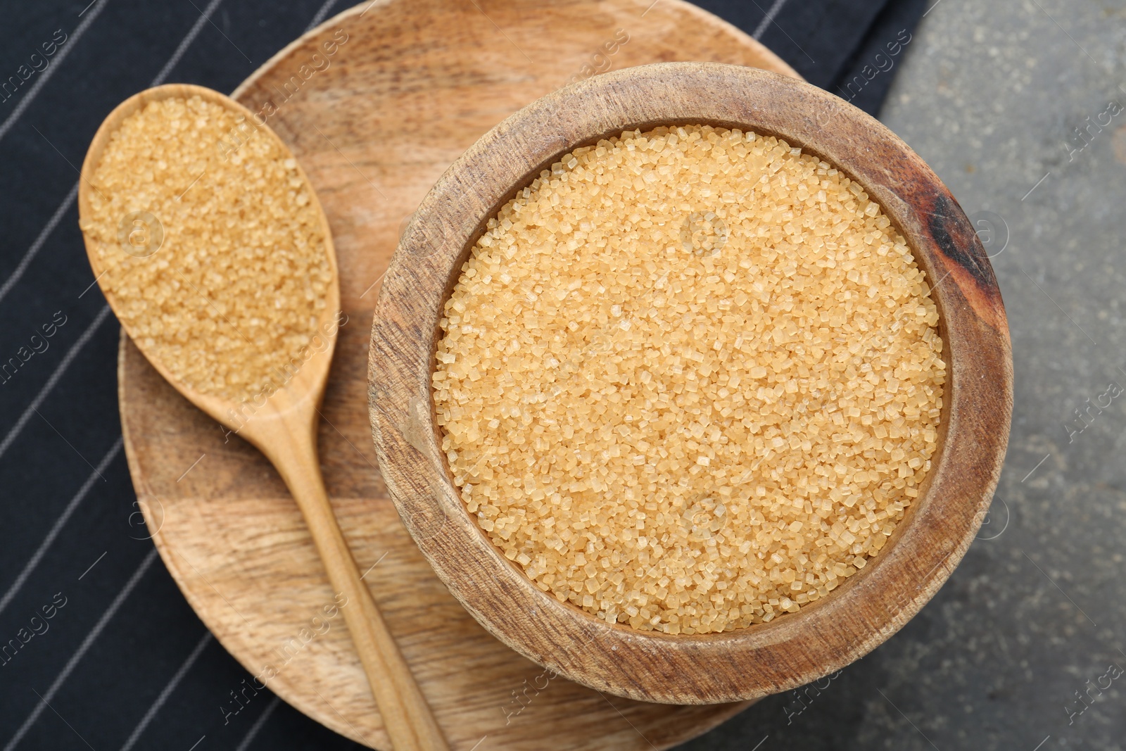 Photo of Brown sugar in bowl and spoon on grey table, top view