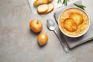 Tasty homemade french onion soup served on grey table, flat lay. Space for text