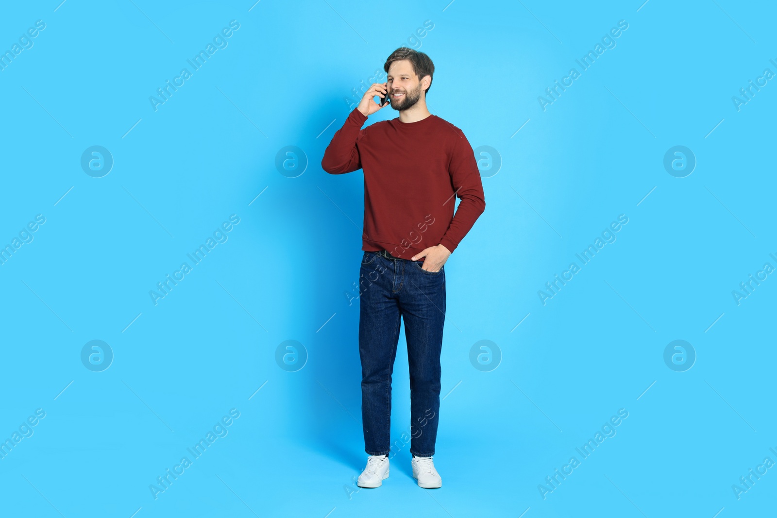 Photo of Man talking on smartphone against light blue background