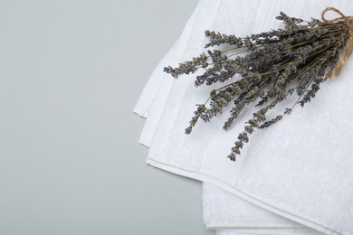 Photo of White terry towels and lavender flowers on light grey background, top view. Space for text