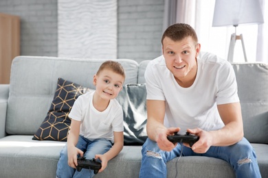 Photo of Happy dad and his son playing video games at home. Father's day celebration