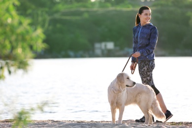 Young woman with her dog together on beach. Pet care