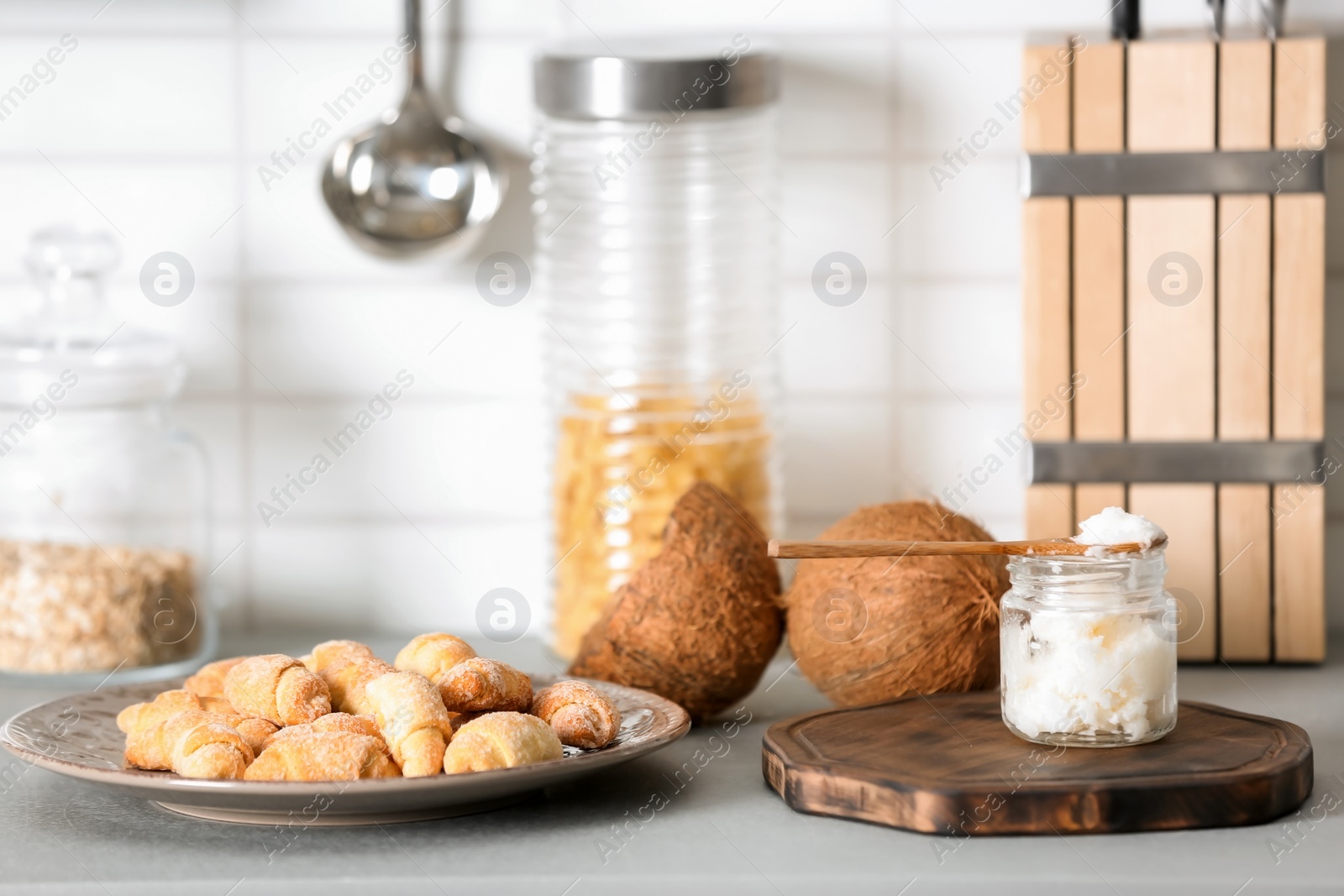 Photo of Jar with coconut oil and tasty pastry on table in kitchen. Healthy cooking