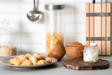 Jar with coconut oil and tasty pastry on table in kitchen. Healthy cooking