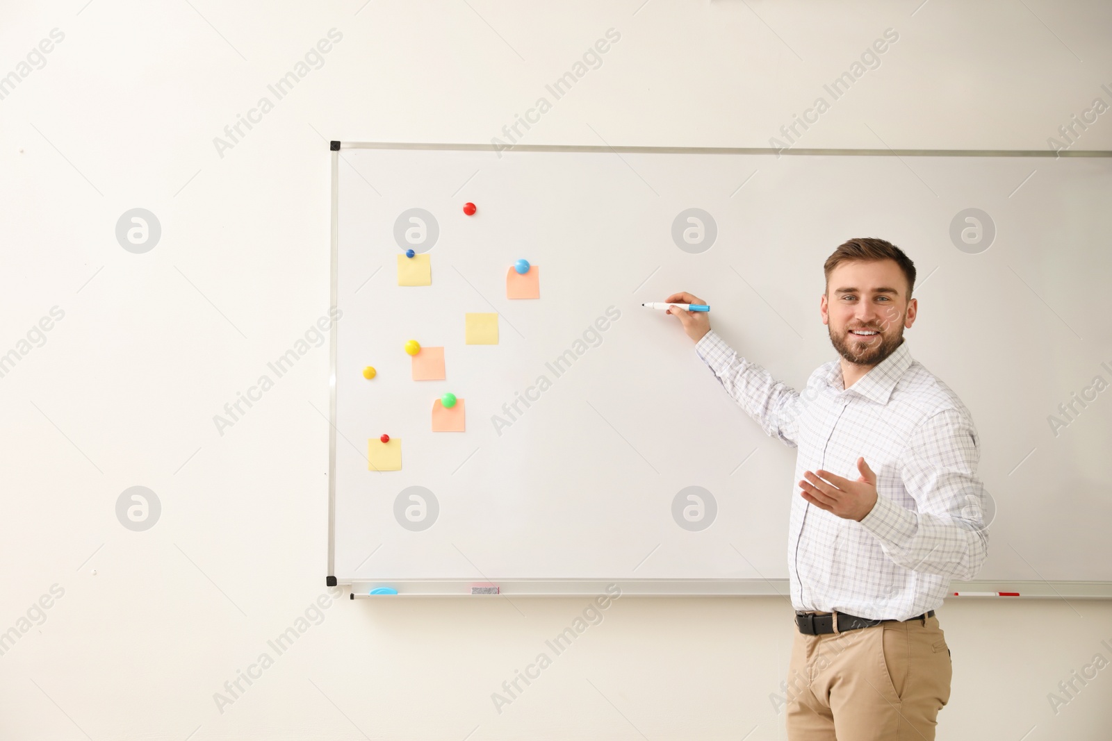 Photo of Portrait of young teacher writing on whiteboard in classroom