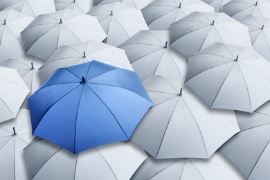 Image of Blue umbrella standing out of other ones, above view