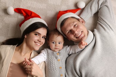 Photo of Happy couple with cute baby on floor, top view. Christmas celebration