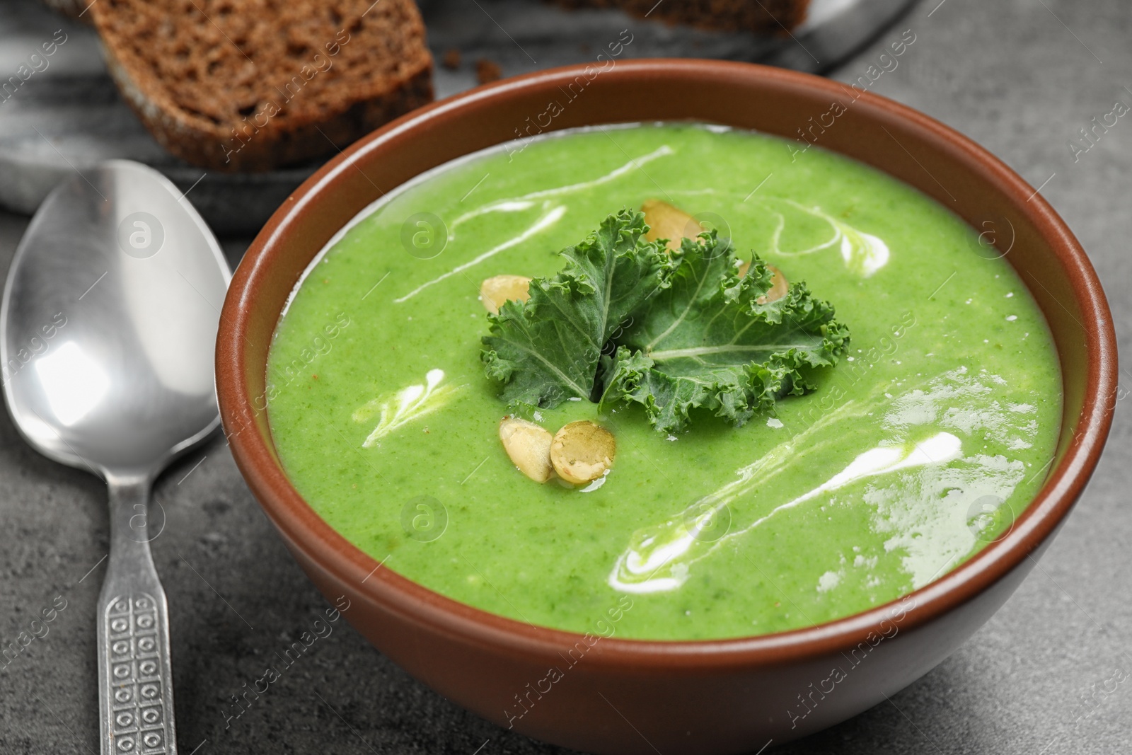 Photo of Tasty kale soup served on grey table, closeup