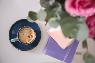 Cup of coffee and flowers on table, top view