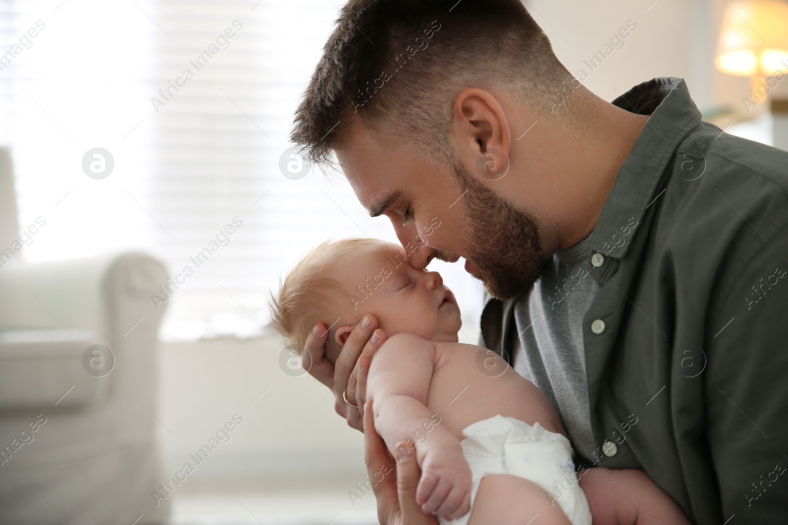 Photo of Father with his newborn son at home