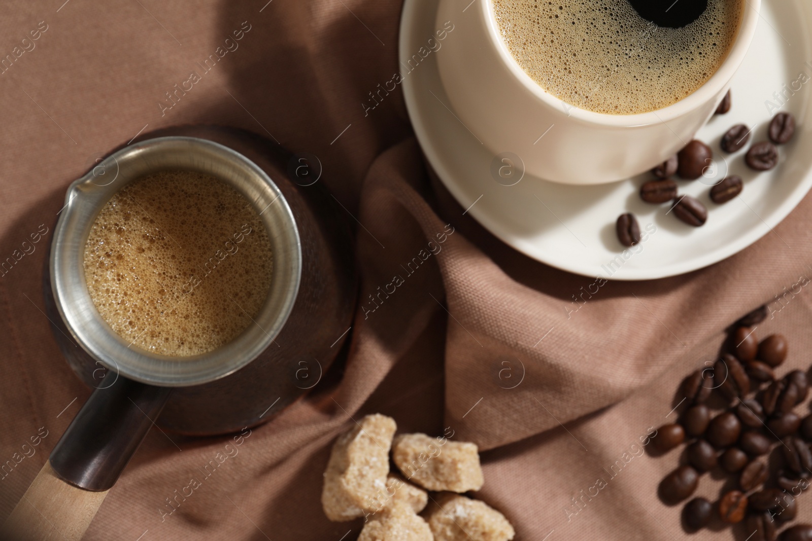 Photo of Turkish coffee. Cezve and cup with hot aromatic coffee, beans and sugar on table, flat lay