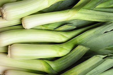 Photo of Fresh raw leeks as background, closeup. Ripe onion