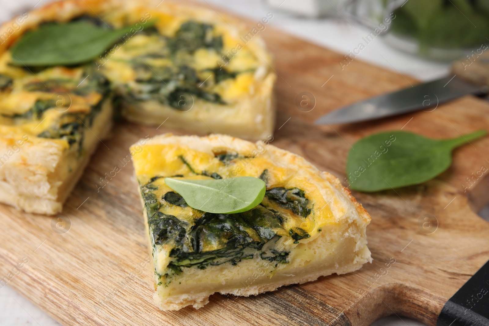 Photo of Piece of delicious pie with spinach on wooden board, closeup