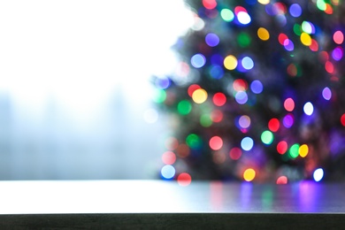 Photo of Blurred view of beautiful Christmas tree with colorful lights near window indoors, focus on table. Space for text