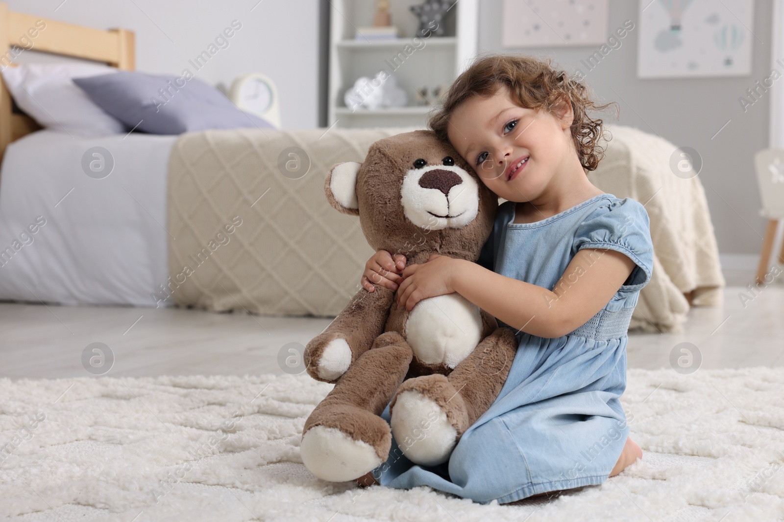 Photo of Cute little girl with teddy bear on floor at home