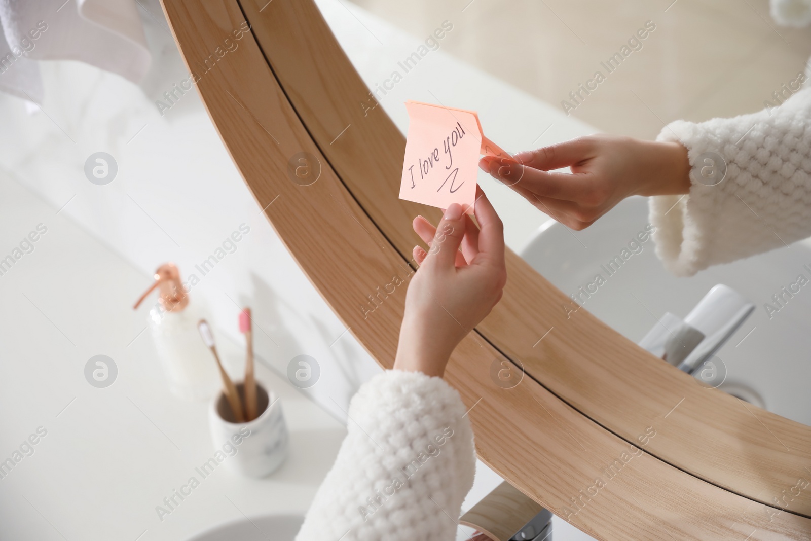 Photo of Woman with sticky note saying I Love You near mirror in bathroom, closeup. Romantic message