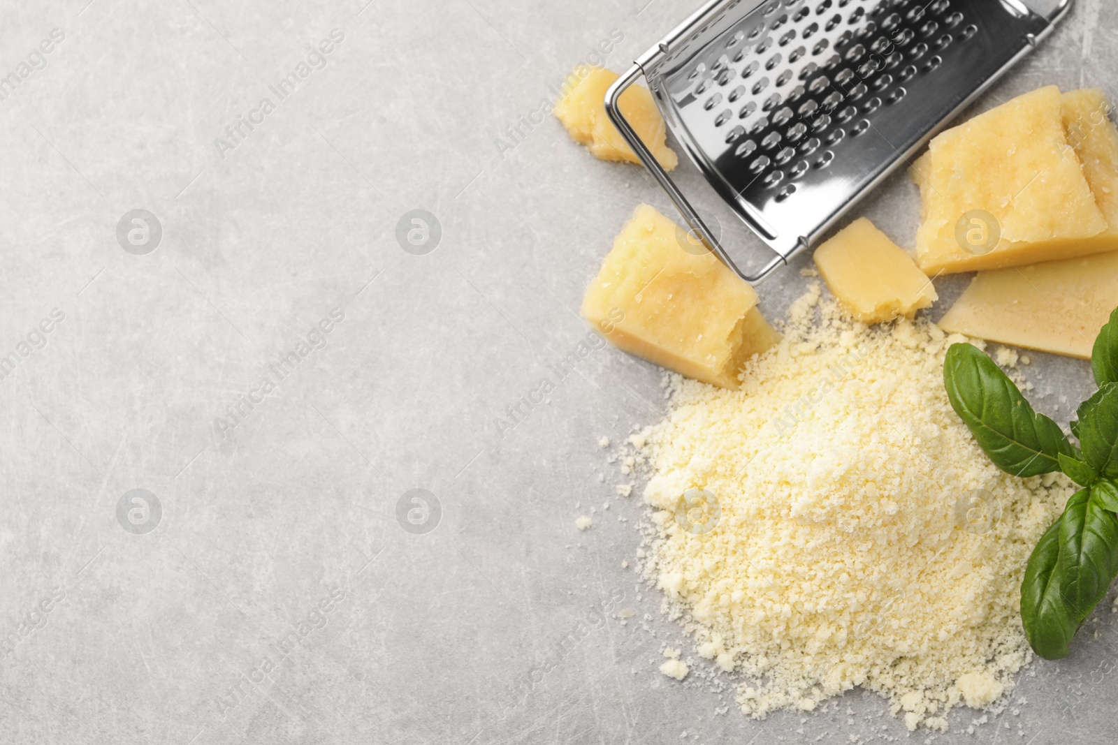 Photo of Flat lay composition with grater, basil, parmesan cheese on grey table. Space for text