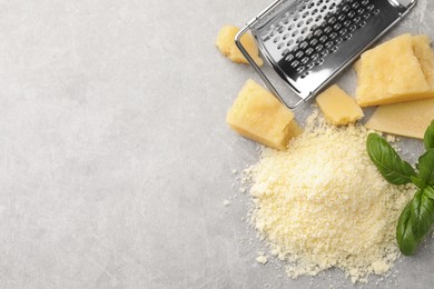 Flat lay composition with grater, basil, parmesan cheese on grey table. Space for text