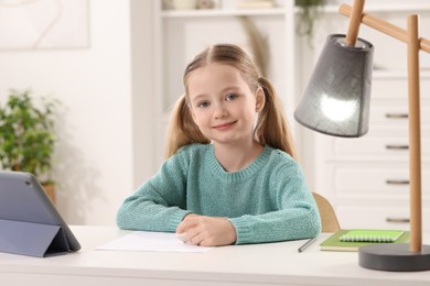 Photo of Girl with eraser at white desk in room