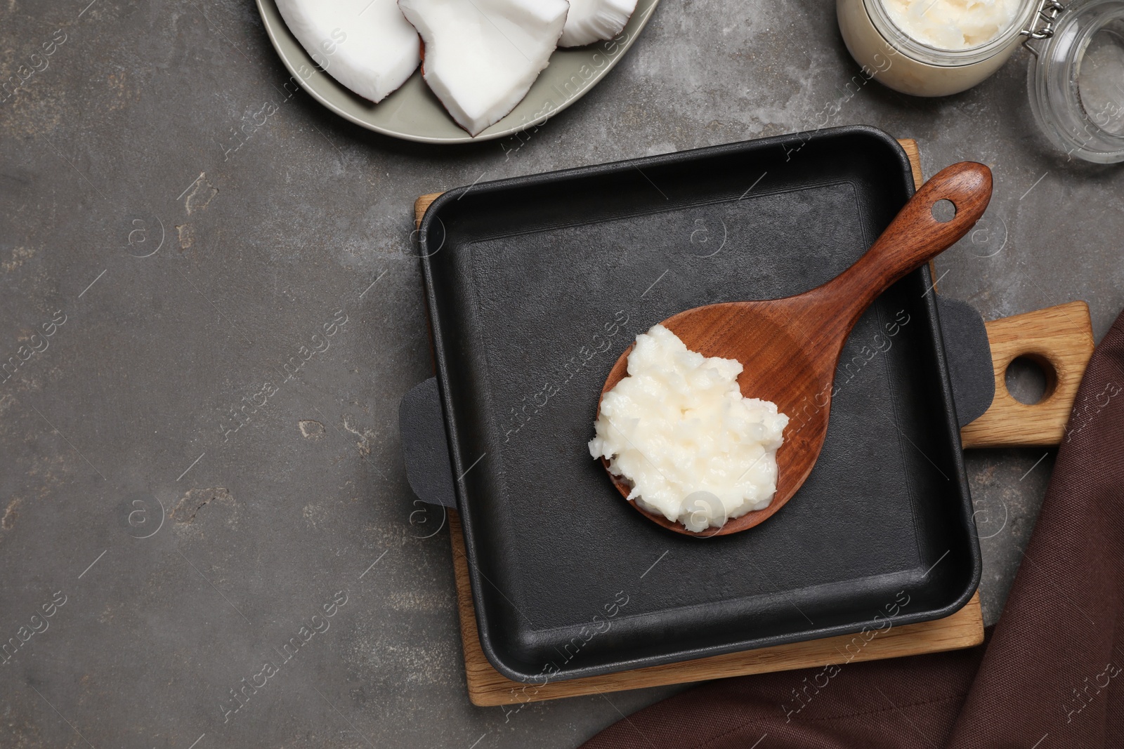 Photo of Baking dish with coconut oil and wooden spoon on grey table, flat lay. Space for text