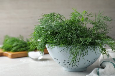 Fresh dill in colander on white table