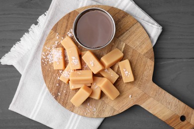 Yummy caramel candies and sea salt on wooden table, top view