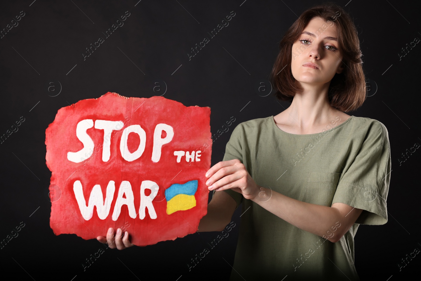 Photo of Sad woman holding poster with words Stop the War on black background