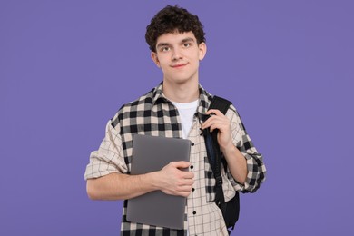 Portrait of student with backpack and laptop on purple background