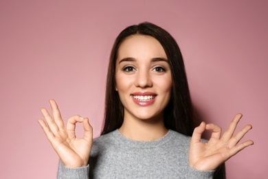 Photo of Woman showing OK gesture in sign language on color background