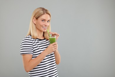 Photo of Happy woman with glass of fresh celery juice on light grey background. Space for text