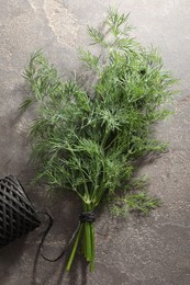 Bunch of fresh dill and spool of thread on grey textured table, flat lay