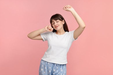 Photo of Woman in pyjama stretching on pink background