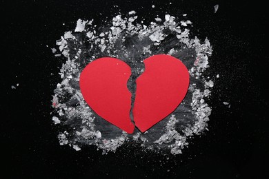 Photo of Halves of torn paper heart and ash on black background, top view