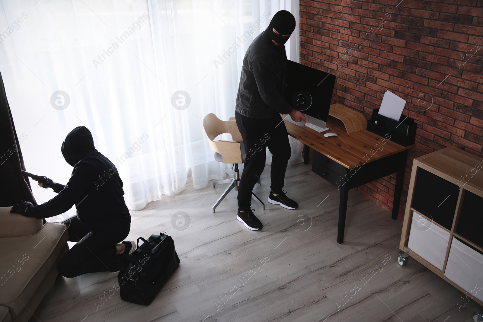 Photo of Dangerous masked criminals with weapon stealing computer from house