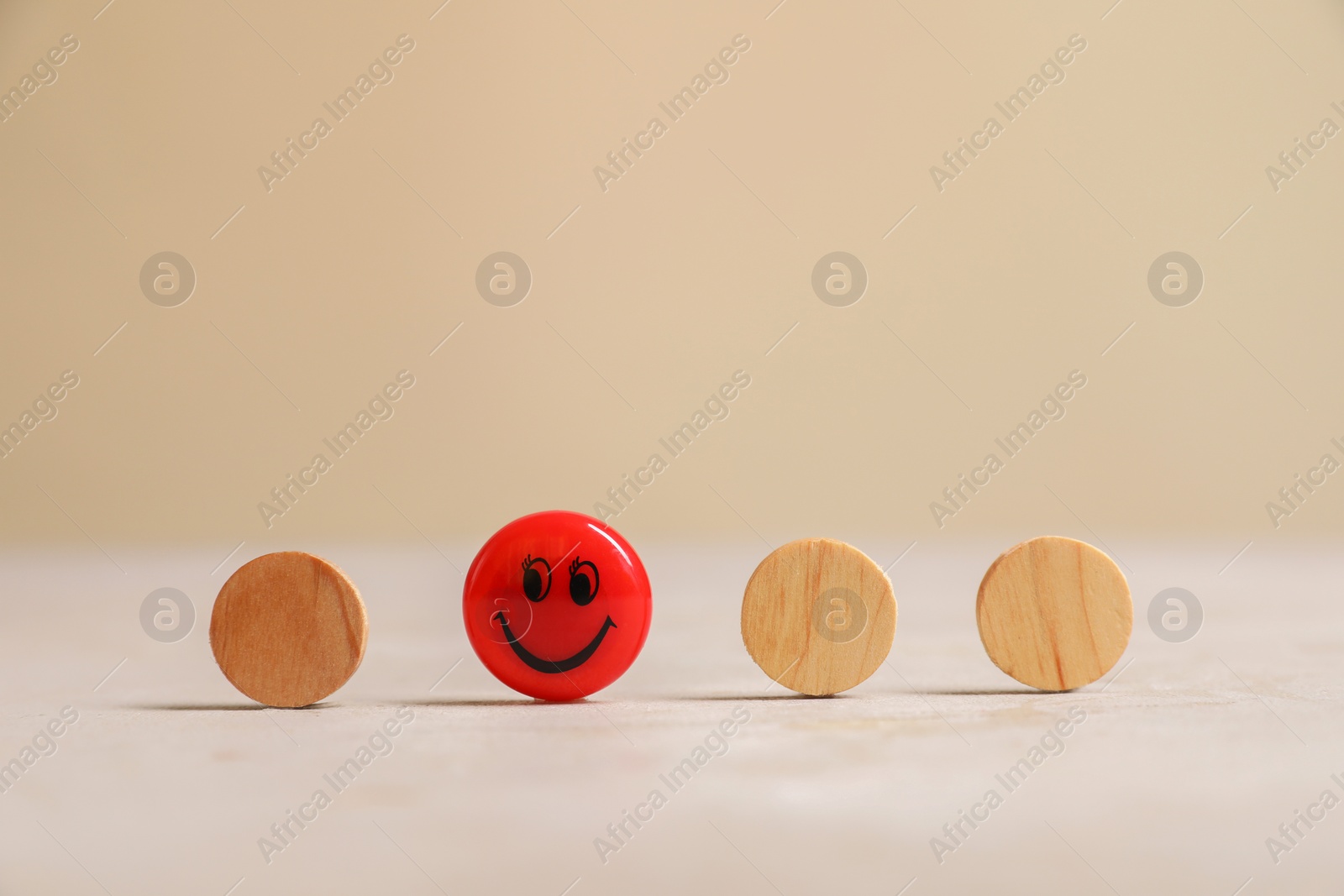 Photo of Choice concept. Red magnet with happy emoticon among wooden circles on light table