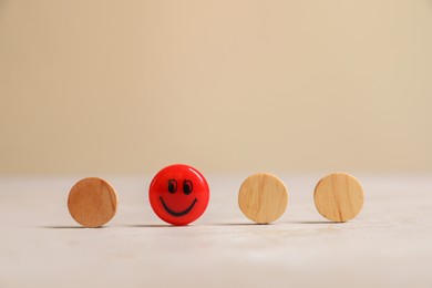 Choice concept. Red magnet with happy emoticon among wooden circles on light table