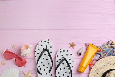 Flat lay composition with flip flops and beach accessories on pink wooden background. Space for text