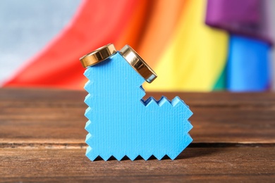 Photo of Heart figure with wedding rings and rainbow flag on background. Gay marriage