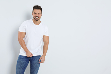 Photo of Young man in stylish jeans on light background. Space for text