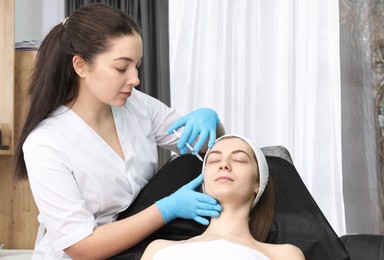 Photo of Cosmetologist giving facial injection to patient in clinic. Cosmetic surgery