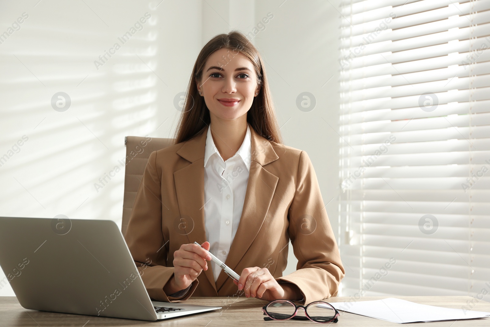 Photo of Portrait of beautiful young businesswoman with laptop at table in office