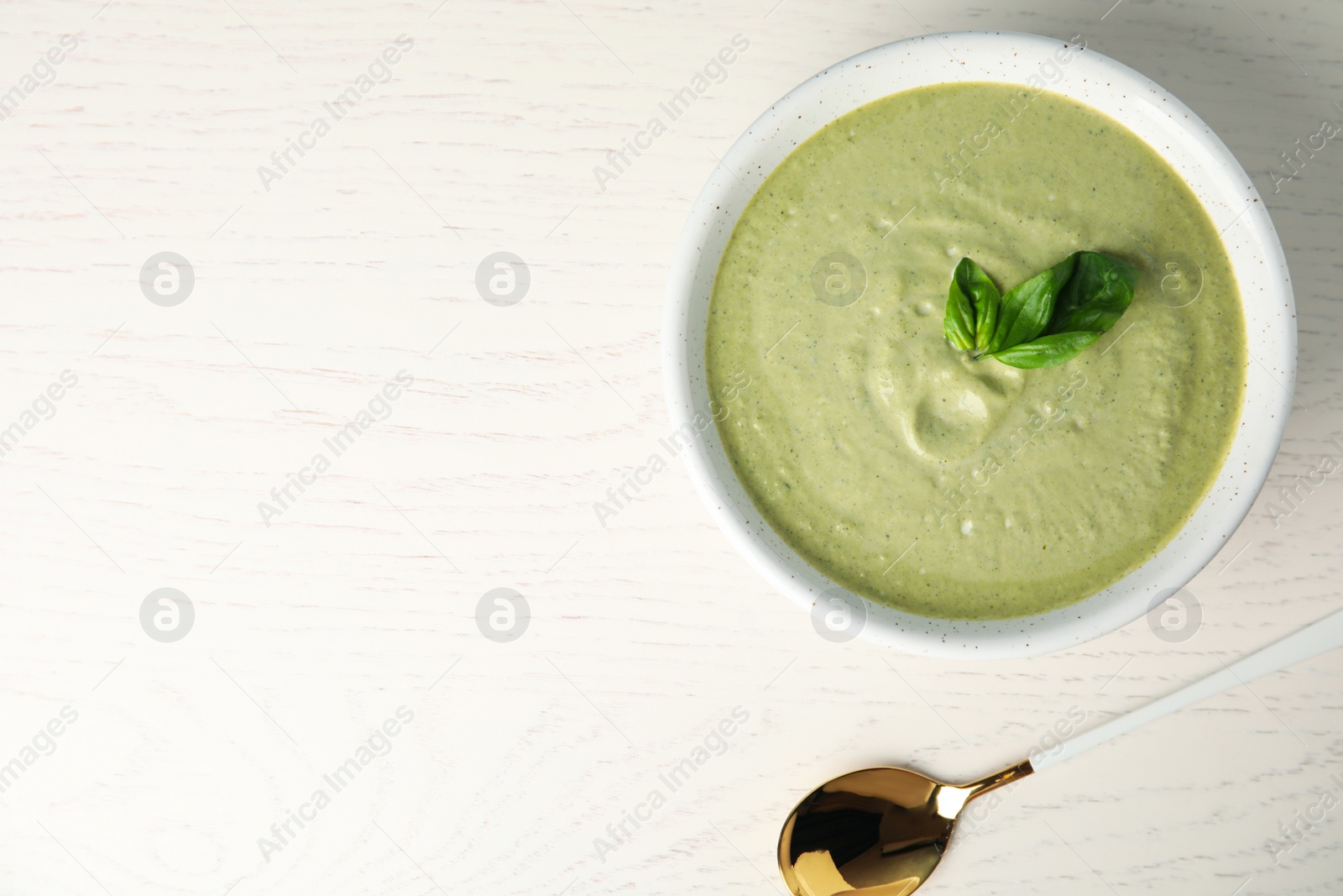 Photo of Delicious broccoli cream soup served on white wooden table, flat lay. Space for text