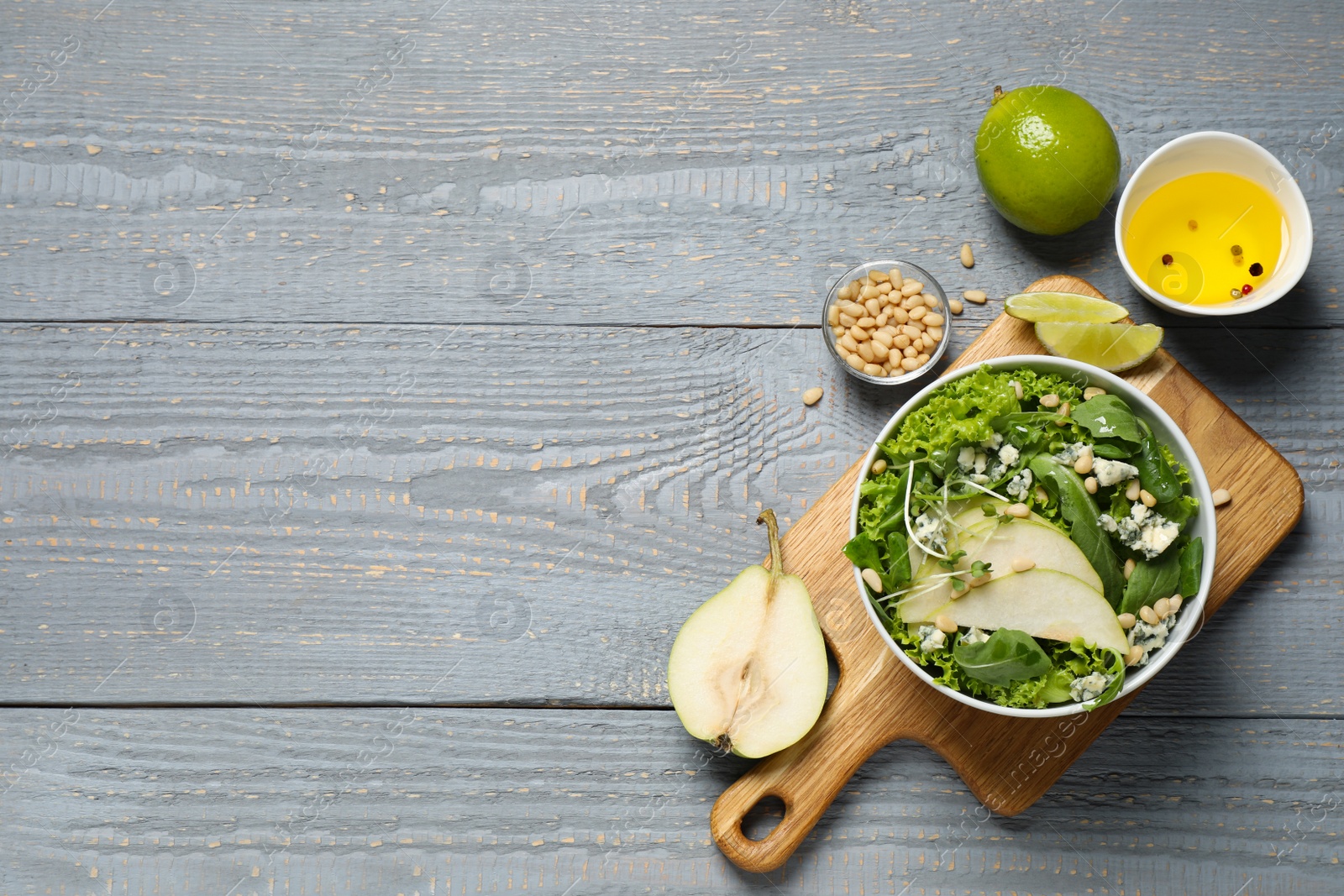 Photo of Fresh salad with pear and ingredients on grey wooden table, flat lay. Space for text