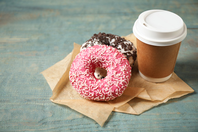 Photo of Yummy donuts with sprinkles and paper cup on wooden table