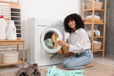 Photo of Woman putting laundry into washing machine indoors