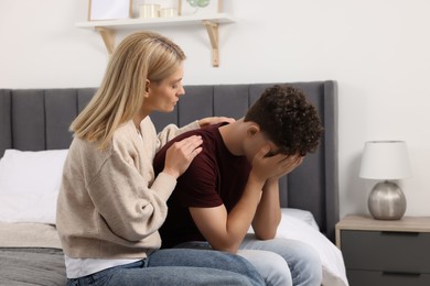 Photo of Mother consoling her upset son in bedroom. Teenager problems