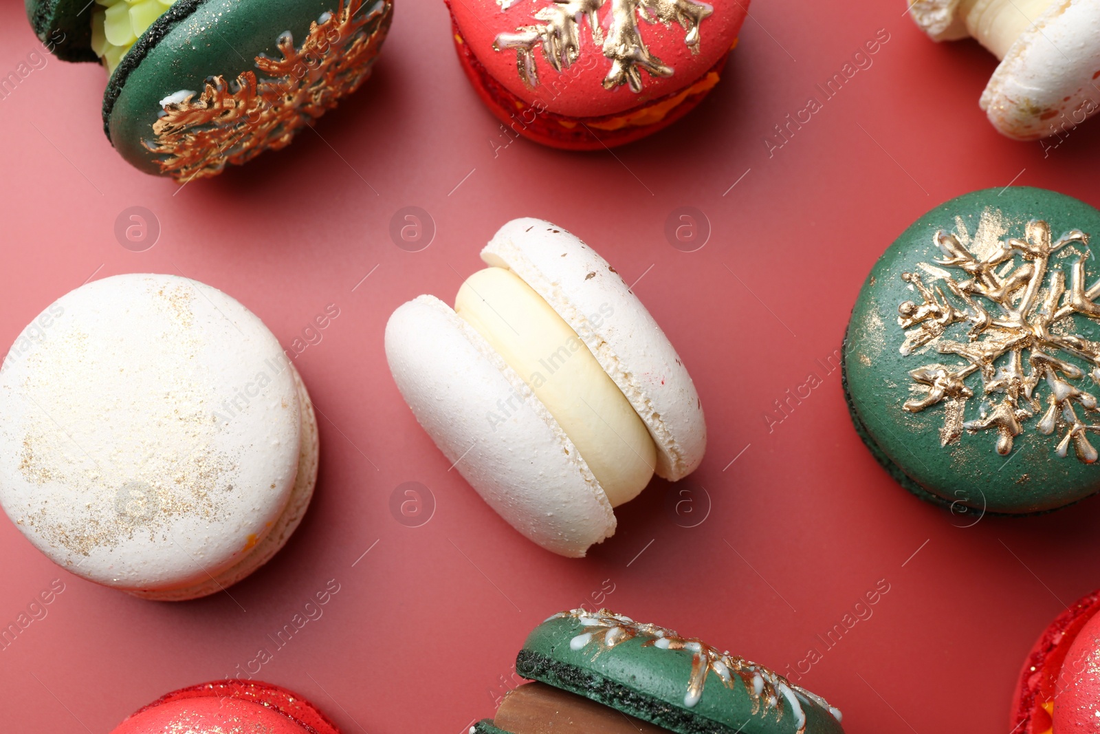 Photo of Beautifully decorated Christmas macarons on red background, flat lay