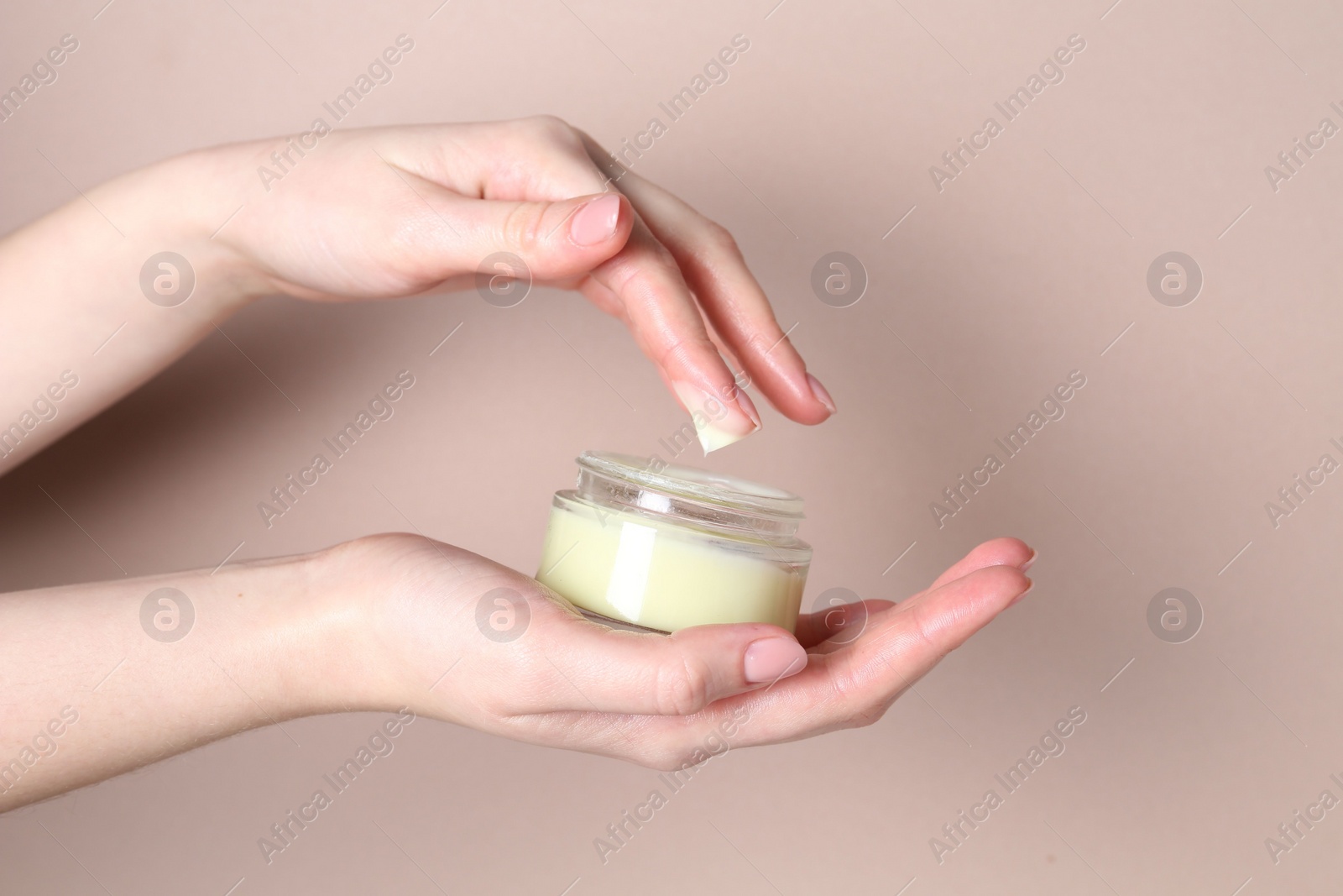 Photo of Woman with jar of cream on beige background, closeup