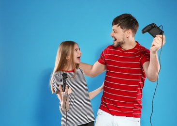 Photo of Emotional man and teenage girl playing video games with controllers on color background